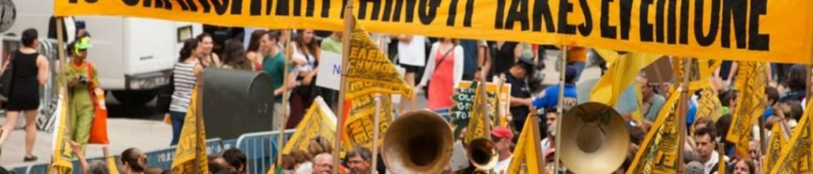 Protest sign reading "To change everything, it takes everyone"