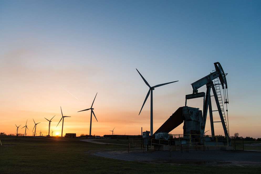 Oil pump jack and wind turbines at sunset in central Oklahoma near Calumet.  | Center for International Environmental Law