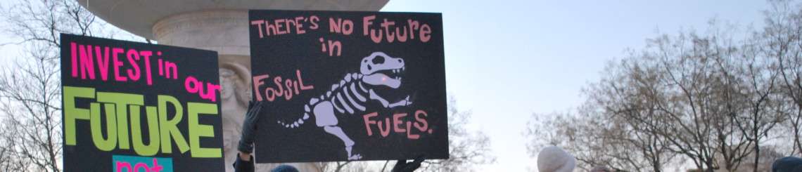 Protesters holding signs reading "Invest in our future, not fossil fuels" and "There's no future in fossils" at a divestment protest