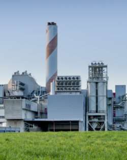 red and grey striped smoke stack in front of a grey industrial facility