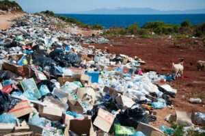 large pile of trash on a dirt, a waterway is in the distant background