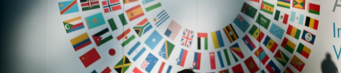 man on a cell phone walks past a wall covered in multiple countries' flags at the World Bank