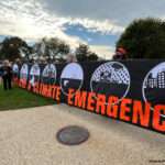 group of people are holding a sign with the words "climate emergency" in bold, orange letters