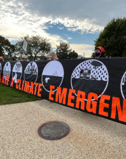 group of people are holding a sign with the words "climate emergency" in bold, orange letters