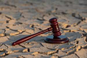 A judge's gavel resting on dry ground, symbolizing the legal system, climate change