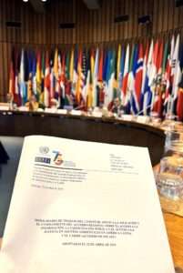 A document on a table surrounded by various flags in a room.