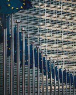 Picture of European Union Flags in a line set in front of a building which is the European Commission in Brussels, Belgium.
